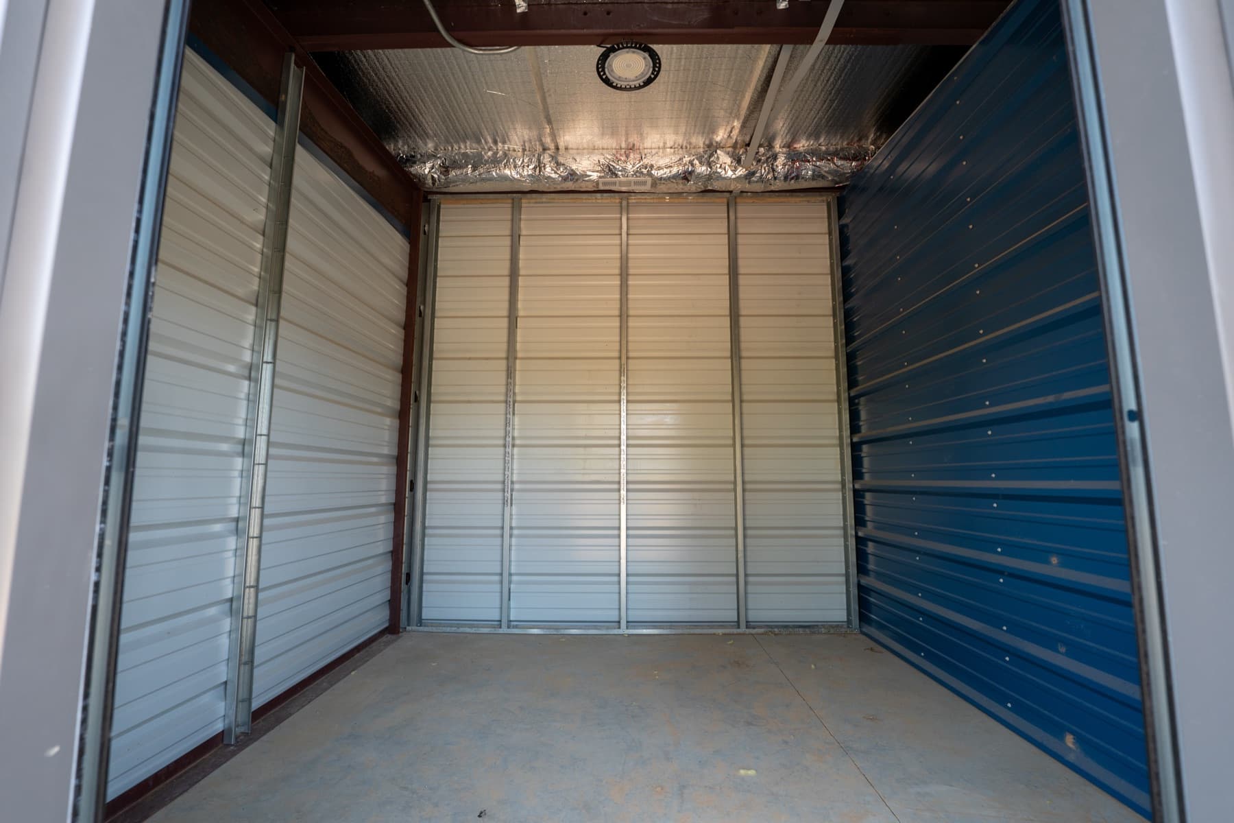 Inside an empty climate-controlled unit: insulated ceiling, overhead light, steel walls